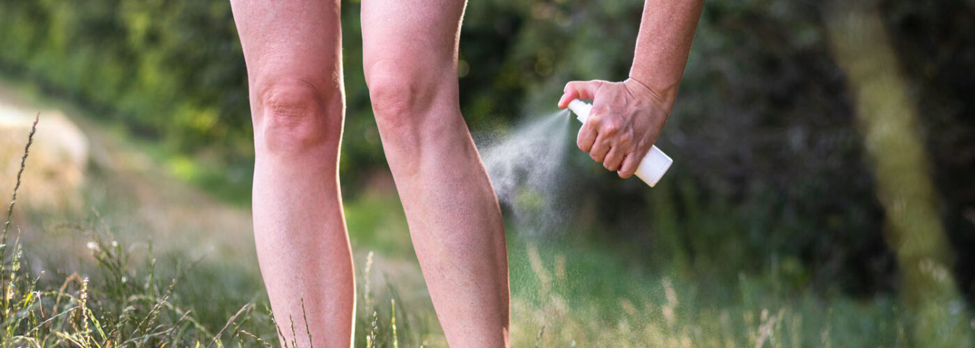 Woman spraying bug repellent on legs