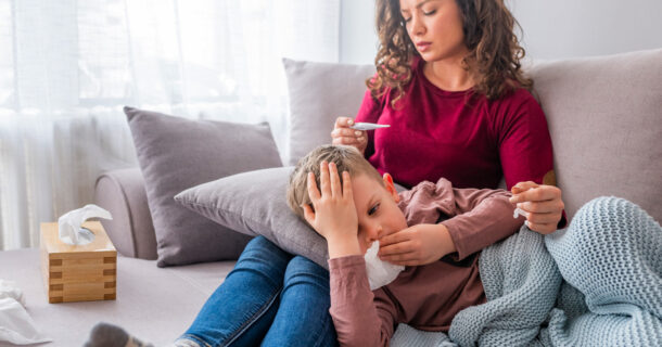 Mother comforting sick child on the couch